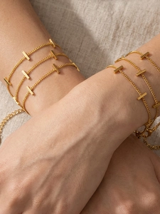 Close-up of stacked gold rope chains with rectangular bars on a linen background
