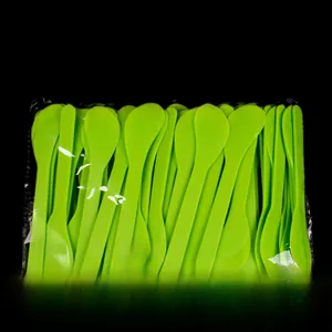Detailed view of 100 green plastic spatulas for mask mixing in a clear bulk pack
