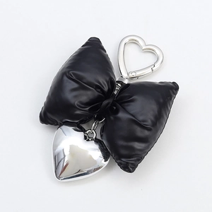 Puffy black bow keychain with silver heart carabiner and heart pendant on white background