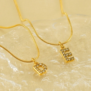 Detailed macro of gold snake chains with D and E initial pendants set in sparkling zircon