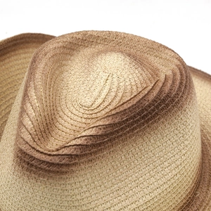 Detail of woven straw cowboy hat with a brown gradient edge and textured fiber patterns