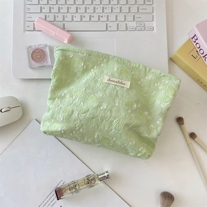 Detail of light green floral lace makeup bag with woven label and zipper closure