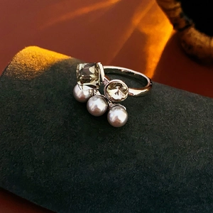 Detail of silver vintage ring featuring square grey gem, amber stone and three pearls