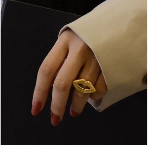 Detail of a 18K gold plated lip shaped ring worn on finger with artistic shadow