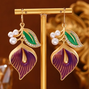 Elegant purple calla lily earrings with white pearls and gold accents on a display