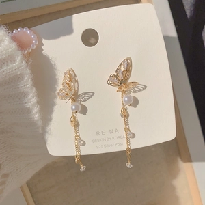Macro detail of tassel earrings with butterfly motifs, pearls, and 925 silver posts