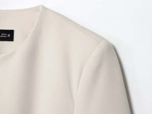 Détail du blazer beige montrant la texture du tissu, les coutures du col et l'étiquette