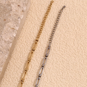 Macro detail of gold and silver paperclip link chain bracelets on a textured background