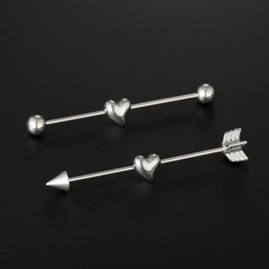 Macro shot of stainless steel industrial piercing barbells with heart and arrow motifs