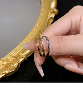 Close-up of gold and silver faceted rings on model fingers with vintage gold frame background