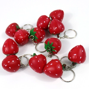 Close-up of cute red strawberry keychains with green leaves on a white background