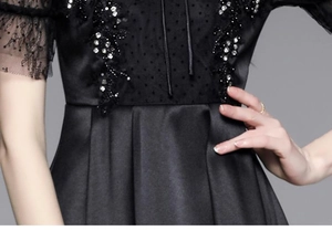 Detail of beaded floral embroidery and lace stitching on black luxury satin dress