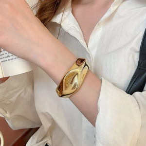 Detailed close-up of a wide irregular lava texture gold cuff on a female model wrist