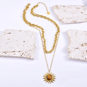 Collier double couche doré avec pendentif soleil en œil de tigre sur socle en travertin
