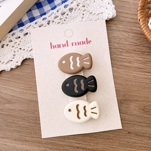 Detailed view of three cute cartoon fish hair clips on a handmade card display