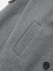 Detailed view of grey wool blend coat with flap pocket and premium fabric texture