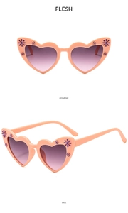 Detail view of heart-shaped kids' sunglasses in flesh pink with purple floral accents