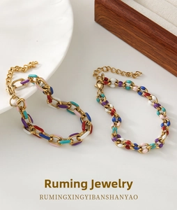 Macro view of multi-colored enamel and gold-plated chain link bracelets with lobster clasps