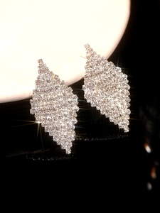 Macro shot of sparkling green leaf-shaped earrings with micro-pave crystals on black mirror