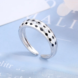 Macro view of adjustable silver ring featuring black and white checkered enamel patterns