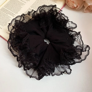 Détail d'un chouchou en dentelle noire élégante avec texture plissée sur un livre