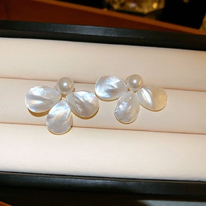 Macro detail of elegant pearl flower earrings with mother of pearl petals and a glossy finish