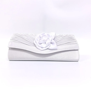 Detail of white satin evening clutch featuring handmade rose and pleated fabric texture