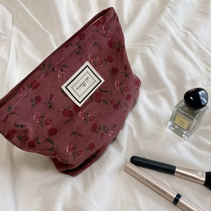 Close-up of vintage floral corduroy makeup bag in burgundy with zipper and label