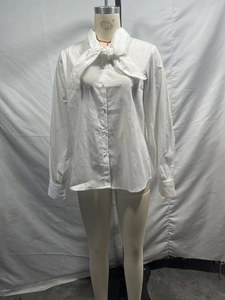Close-up of white chiffon shirt with pussy-bow tie, lace trim and pearl buttons