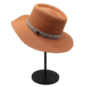 Detailed close-up of a brown straw hat with a sparkling rhinestone band and M logo