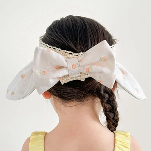 Close-up of pink floral pattern and white lace edge on girl's bow headband