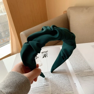 Détail d'un serre-tête plissé vert foncé avec étiquette fait main sur le tissu