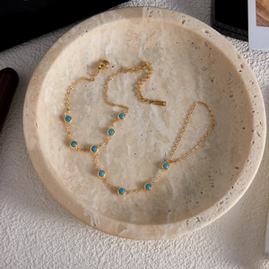 Detail einer vergoldeten Edelstahlkette mit neun blauen Türkissteinen und Verschluss