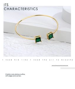 Close-up of gold open bracelet featuring two square emerald green zircon gemstones
