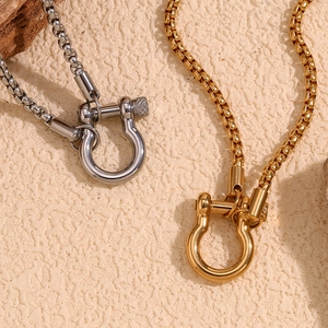 Close-up of gold and silver horseshoe shackle clasps on minimalist metal chain necklaces