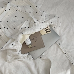 Flat lay of a floral canvas tote bag on white linen with lifestyle essentials inside