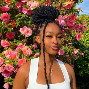Extensiones de rastas negras bohemias en modelo con fondo floral de rosas