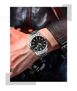 Men's silver steel chronograph watch with black dial worn on wrist under dramatic red light