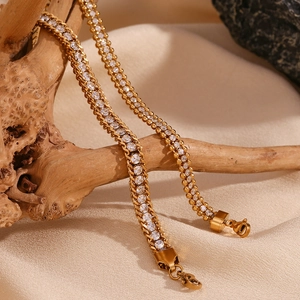 Close-up of triple-layered woven 18K gold-plated bracelet with zircons on wooden stand