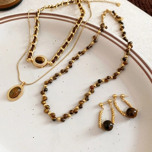 Dettaglio del set di gioielli placcati in oro 18 carati con pietre occhio di tigre su vassoio
