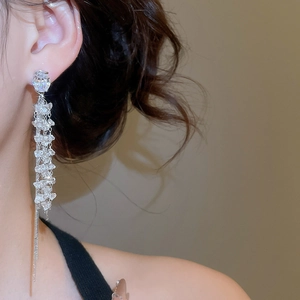 Macro detail of silver long tassel earrings with sparkling zircon crystals on a model