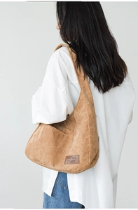 Close-up of khaki corduroy shoulder bag showing fabric texture and leather logo detail