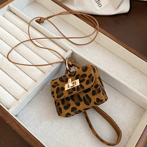 Detail of leopard print mini bag charm with golden clasp in a velvet jewelry tray
