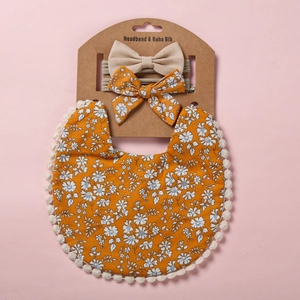 Détail d'un bavoir boho pour bébé à fleurs avec dentelle et bandeaux à nœuds