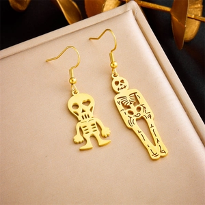 Detailed view of asymmetrical gold-plated skull and skeleton drop earrings on display