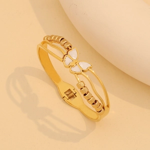 Detailed close-up of golden butterfly bracelet with white shell inlay and bead accents