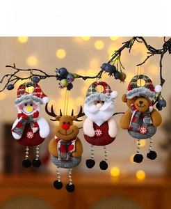 Detail of four Christmas plush ornaments featuring Santa and Reindeer hanging on a branch