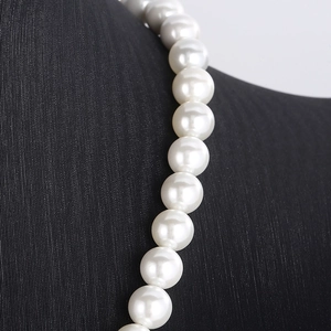 Detailed macro view of white round shell pearls with high luster on a Cuban link chain