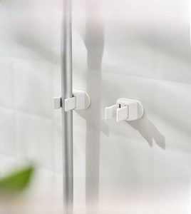 Adhesive wall-mounted mop and broom holder with U-shaped grip on white tiled wall