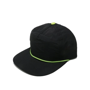 Détail de casquette noire avec cordelette vert néon et bouton assorti sur le dessus